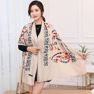 Detailed view of floral ethnic embroidery on beige cashmere shawl with soft fringes