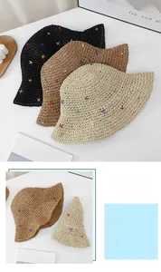 Detail of colorful cross-stitch embroidery on foldable woven straw bucket sun hat for women