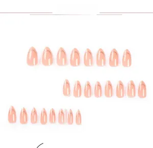 Detail of nude pink press-on nails with golden glitter French tips on white background