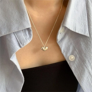 Close-up of a 925 sterling silver heart pendant necklace worn by a model in soft light