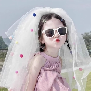 Detail of a white mesh veil with colorful pom-poms for girls outdoor party photography