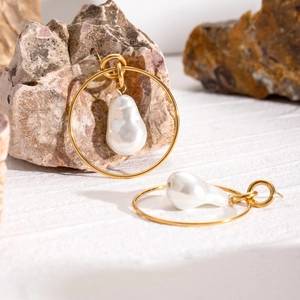 Baroque pearl earrings with large gold hoops and organic white pearls on stone background
