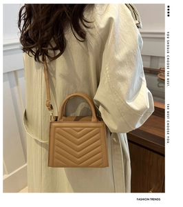 Close-up of khaki chevron quilted square handbag with gold hardware and top handle