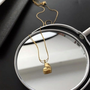 Creative close-up of gold heart pendant necklace reflecting on a circular mirror
