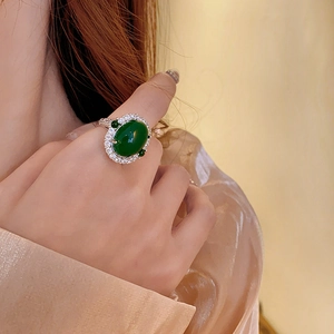 Detailed view of an oval green zircon ring with a luxury halo setting on a model's hand