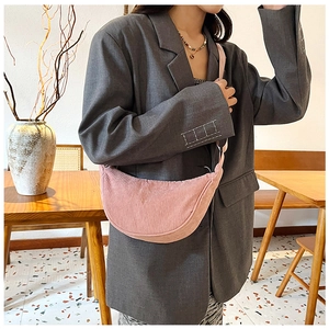 Close-up of pink corduroy crescent bag with adjustable strap worn on shoulder