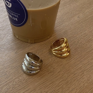 Detail of gold and silver multi-layer geometric rings on a wooden surface