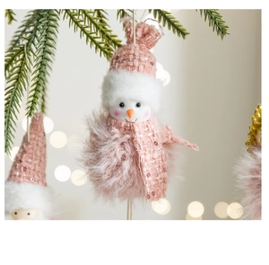 Close-up of pink plush Christmas snowman hanging on pine branch with sequins and soft bokeh