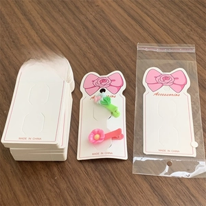 Detail view of pink and green flower hair clips on a white accessories display card