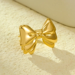 Elegant gold bow-shaped ring and scarf buckle accessory on a textured background