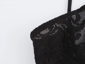 Detailed macro view of black lace fabric and intricate hollow-out patterns on the dress