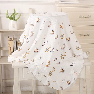 Detail of white muslin baby blanket with rainbow print and ruffled edges for strollers