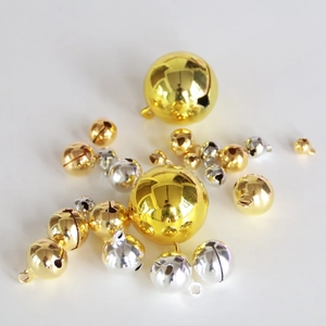 Detailed close-up of shiny gold and silver metal bells in various sizes for DIY crafts