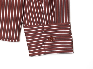 Close-up of red and white striped shirt cuff showing fine stitching and button detail