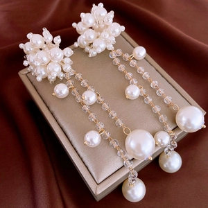 Détail de boucles d'oreilles à pompon perlé et fleurs avec des accents dorés raffinés