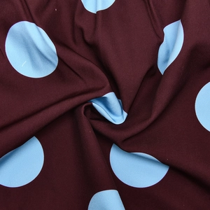 Close-up of brown fabric with light blue polka dots and a smooth draped texture