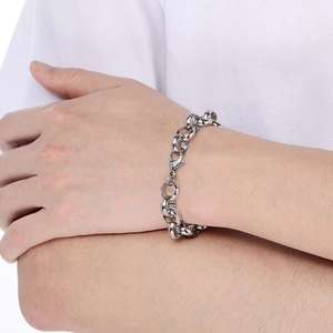 Close-up of a chunky silver stainless steel link chain bracelet on a model's wrist