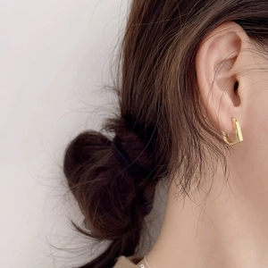 Close-up of minimalist gold square hoop earrings worn by a model for elegant style