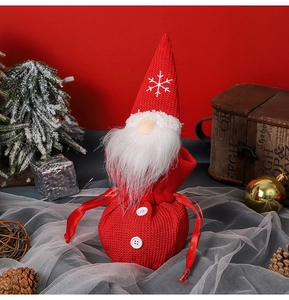 Detail of red knitted Christmas gnome candy bag with white beard and snowflake embroidery