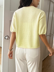 Close-up of light yellow knit fabric texture on the back of a women casual short sleeve sweater