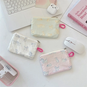 Three cat print fabric pouches for coins or earphones on a desk with a laptop