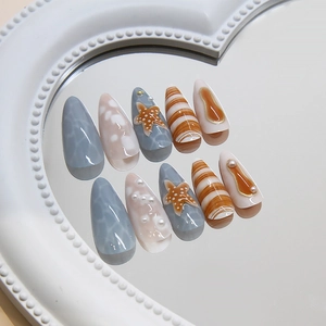 Ocean theme press-on nails with starfish, pearls, and shells on a heart mirror tray