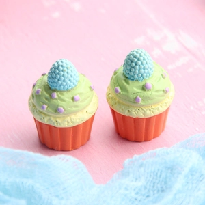 Detailed macro view of two resin cupcake miniatures with green frosting and blue berries