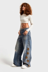 Detail of high waisted wide leg jeans featuring intricate yellow floral embroidery on blue denim