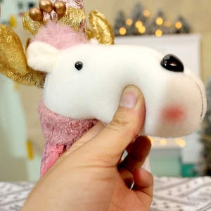 Close-up of soft plush Christmas reindeer toy being squeezed to show premium resilience