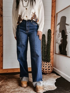 Detail van donkerblauwe jeans met hoge taille, wijde pijpen en decoratieve naad voorop