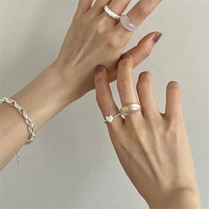 Detail showing a 925 silver heart ring paired with resin rings and a chain bracelet