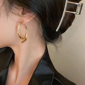 Close-up of elegant gold twisted hoop earrings worn by a model in soft lighting