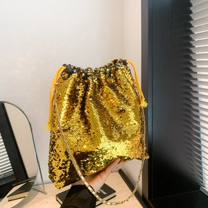Detail of gold sequin bucket bag with drawstring closure and golden chain strap