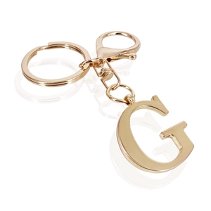 Macro shot of minimalist golden stainless steel keychain featuring a polished capital letter G