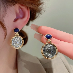 Close-up of vintage coin earrings with blue gemstone and silver portrait relief