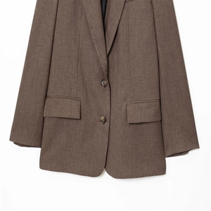 Détail du blazer marron foncé avec fermeture à deux boutons et poches classiques à rabat