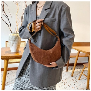 Brown corduroy crescent hobo bag shown in a cozy cafe setting with natural light