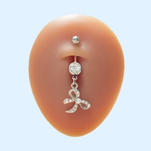 Piercing de nombril nœud argenté avec strass sur un moule en silicone de ventre