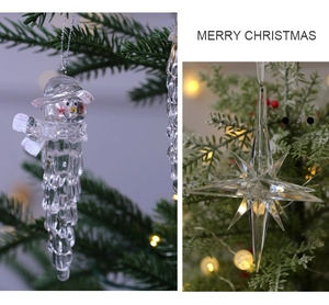 Detail of transparent acrylic snowman and star pendants on a lit Christmas tree