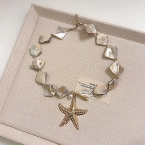 Detail of pink mother-of-pearl choker with a gold starfish pendant and lobster clasp