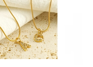 Detailed close-up of golden stainless steel snake chain and crystal-set A and C charms