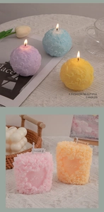 Macro detail of embossed rose patterns on scented candles with burning cotton wicks