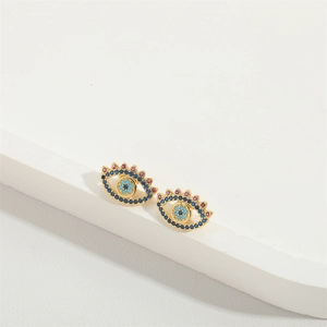 Close-up of gold stud earrings with colorful evil eye zircon stones on white stand