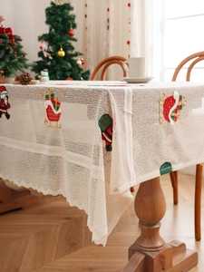 Close-up of cream lace tablecloth with festive red Santa and sleigh embroidery