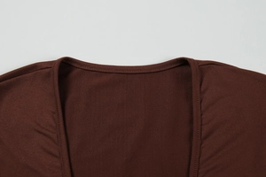 Detail of the deep V-neckline and fine double-stitched hem on the dark brown knit dress