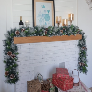 Detailed view of snowy Christmas garland with pine cones on a classic white fireplace