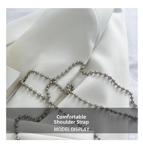 Polished silver metal ball chain strap for handbags resting on white silk fabric