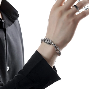Close-up of a silver titanium steel Cuban chain bracelet on a model wearing black