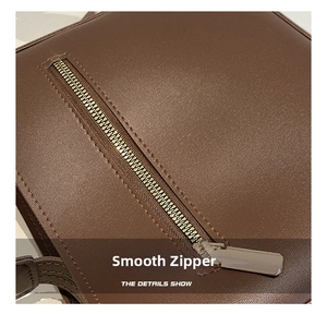 Detail of smooth gold-tone zipper and textured pebble leather on a vintage tote bag