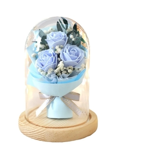 Preserved blue roses with gypsophila in a glass dome on a wooden base gift